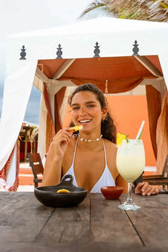 huesped disfrutando de una bebida y de la gastronomia caribeña en un espacio de descanso al aire libre